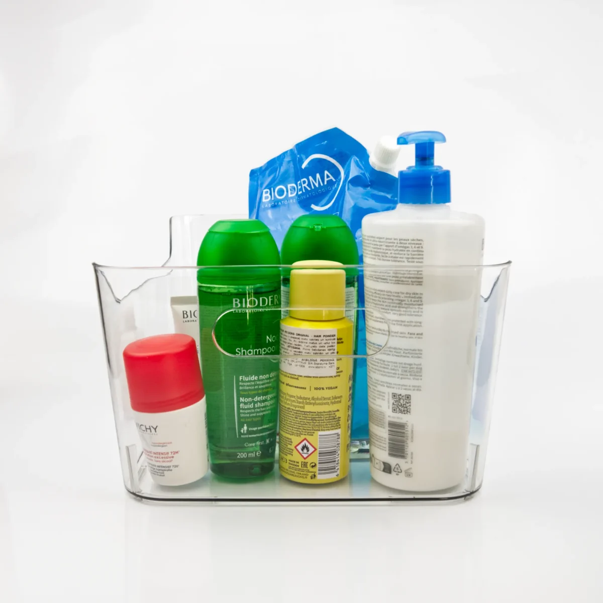 Caurspīdīga plastmasas kaste ar rokturiem, piepildīta ar kosmētikas un higiēnas līdzekļiem